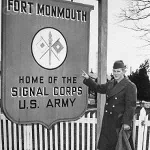 A man standing in front of an historical Fort Monmouth Signal Corps sign